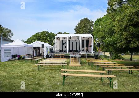 Freilichtbühne, Zelte für technische Ausstattung und als Umkleidekabine, Holzbänke für das Publikum, installiert auf einer Wiese für ein Musikfestival-Event Stockfoto