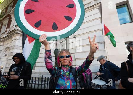 London, Großbritannien. 12. September 2024. Eine Frau hält ein Plakat, das eine riesige Wassermelone darstellt - ein Symbol für palästinensische Identität und Widerstand gegen die Besatzung -, während Unterstützer von Marieha Hussain, 37, vor dem Gericht des Westminster Magistrates zusammentreffen, wo Frau Hussain einer Anklage wegen "rassischer Verschärfung der öffentlichen Ordnung" ausgesetzt ist, weil sie ein Plakat gehalten hat, auf dem Premierminister Rishi Sunak und Ex-Innenministerin Suella Braverman während eines Protests gegen den israelischen Krieg gegen Gaza als Kokosnüsse darstellen. Quelle: Ron Fassbender/Alamy Live News Stockfoto