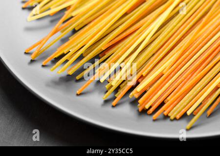 Handwerkliche Bio-Spaghetti-Pasta mit verschiedenen Farben und Texturen auf grauem Küchenteller. Rohzutat. Nahaufnahme Stockfoto