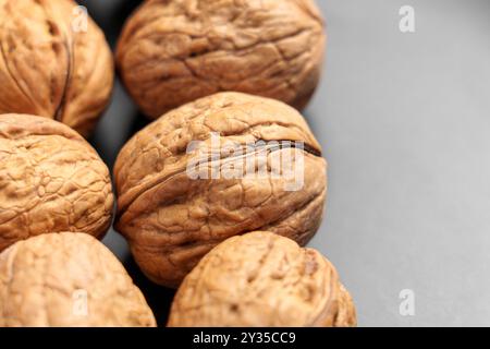 Aus biologischem Anbau stammende Walnüsse in Schalennüssen auf einer luxuriösen schwarzen Keramikplatte. Makro Stockfoto