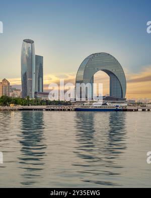 Das Crescent Development Project umfasst eindrucksvolle moderne Gebäude entlang der Küste des Kaspischen Meeres in Baku, Aserbaidschan, die durch die warmen Sonnenuntergänge, die sich auf dem Wasser spiegeln, hervorgehoben werden Stockfoto