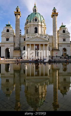 Das Wahrzeichen der Karlskirche und ein reflektierendes Becken auf dem Karlsplatz in Wien. Die Kirche wurde 1737 fertiggestellt. Stockfoto