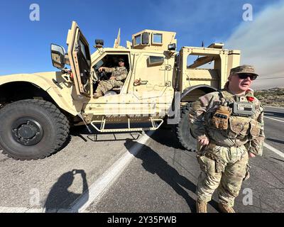 Phelan, Kalifornien, USA. September 2024. Die US National Guard 330 Unit und die Polizei bewachen den Eingang zum Highway 138 (Beekley Rd), der geschlossen wird, um Menschen vom Skigebiet Wright Wood fernzuhalten. Rauch aus dem Bridge Fire im Angeles National Forest, aus der Wüste direkt am Pear Blossom Highway, zwischen Llano und Phelan, Kalifornien. (Kreditbild: © Amy Katz/ZUMA Press Wire) NUR REDAKTIONELLE VERWENDUNG! Nicht für kommerzielle ZWECKE! Stockfoto