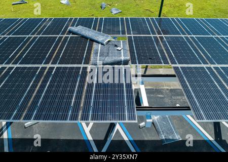 Beschädigt durch Hurrikanwind, Photovoltaik-Solarpaneele auf dem Dach des Parkplatzes zur Erzeugung von ökologischem Strom. Folgen von Nat Stockfoto