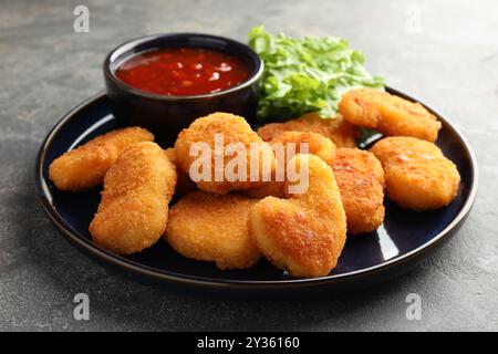 Leckere Chicken Nuggets mit Chili-Sauce auf grauem Tisch Stockfoto