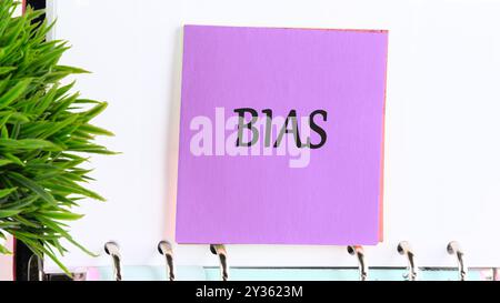 Business-Bias-Konzept. BIAS auf einem violetten Aufkleber auf dem Hintergrund eines weißen Blattes und einer grünen Pflanze im Vordergrund Stockfoto