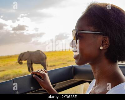 Junge weibliche Touristen lächeln, während sie eine Safari in Afrika in der Nähe eines Elefanten genießen Stockfoto