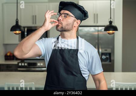 Porträt des Küchenkochs in der Küche. Koch mit dem Zeichen für perfektes Essen. Koch mit Schild für Delicious. Der Koch macht eine leckere Geste durch Küssen Stockfoto