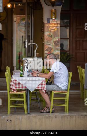 Ein älterer Mann sitzt allein an einem Tisch in einem Restaurant Stockfoto