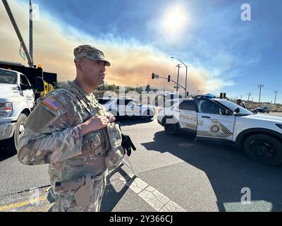 Phelan, Kalifornien, USA. September 2024. Eine Rauchwolke, die durch das Brückenfeuer erzeugt wird, erfüllt den Himmel, während ein Mitglied der Nationalgarde der 330 Einheit und Polizisten den Eingang zum Highway 138 an der Beekley Rd bewachen, um Menschen aus dem Wrightwood-Skigebiet fernzuhalten. Rauch aus dem Bridge Fire im Angeles National Forest, aus der Wüste direkt am Pear Blossom Highway, zwischen Llano und Phelan, Kalifornien. (Kreditbild: © Amy Katz/ZUMA Press Wire) NUR REDAKTIONELLE VERWENDUNG! Nicht für kommerzielle ZWECKE! Stockfoto