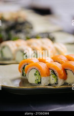 Verschiedene Sushi-Brötchen auf Tellern in einem Restaurant mit einer Auswahl an frischen Zutaten Stockfoto