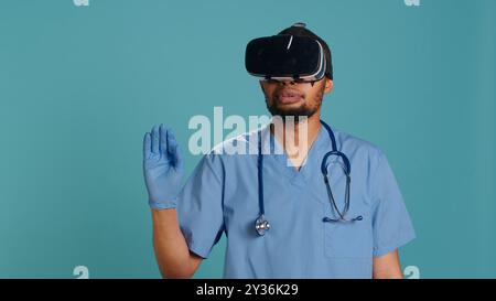 afroamerikaner Arzt trägt eine Virtual-Reality-Schutzbrille und operiert den Patienten. Krankenhausmitarbeiter mit medizinischem High-Tech-vr-Gerät, isoliert über Studio-Hintergrund, Kamera A Stockfoto