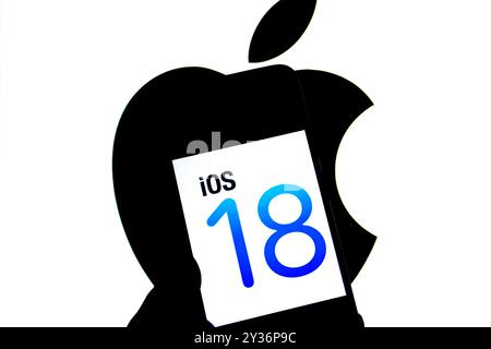 In dieser Fotoabbildung wird ein Apple IOS 18-Logo auf einem Smartphone mit einem Apple-Logo im Hintergrund angezeigt. Stockfoto