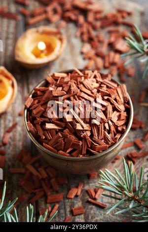 Rote Sandelholzchips in einer Schüssel - Zutat für ätherische Öle, mit Kerzen und Weihnachtsdekoration Stockfoto