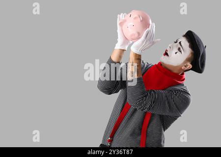 Männlicher Pantomimist mit Schweinebank auf grauem Hintergrund Stockfoto