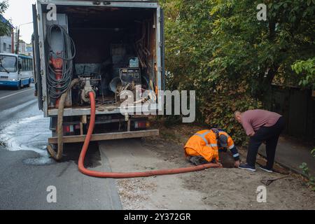 Kanalisationsarbeiter, die den Gullyschacht reinigen und die Kanalisation auf der Straße freimachen. Stockfoto