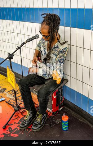 Straßenmusiker sitzt auf dem Verstärker und spielt Gitarre in der Unterführung. Vagrant Lifestyle. Sie spielen in der Unterführung, um ihren Lebensunterhalt zu verdienen. Arbeitslos Stockfoto