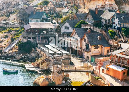 Kleine Küstenstadt mit bezaubernden Häusern und farbenfrohen Booten entlang der ruhigen Uferpromenade. Popeye Village auf Malta Stockfoto