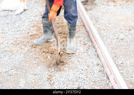 Arbeiter, der auf der Baustelle mit einer Spitzhacke einen Boden gräbt. Stockfoto