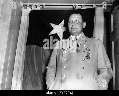 Reichsluftmarschall Hermann Göring posiert vor der Flagge der 36. US-Division auf einer Burg bei Kitzbühel. Göring wurde gefangen genommen, nachdem er von der SS in Berchtesgaden gefangen gehalten wurde. Hitler erließ Anweisungen für seine Hinrichtung. Die Nürnberger Prozesse waren eine Reihe von Prozessen gegen große ns-Militär- und politische Führer. Die Versuche fanden von 1945 bis 1949 statt. Das erste war das Internationale Militärtribunal, das die großen Namen wie Göring, Ribbentrop, Keitel usw. versuchten Es gab 12 Versuche mit Gruppen von Männern, darunter Ärzte, Einsatzgruppen und das militärische Oberkommando. Stockfoto