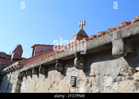 Dubrovnik, Kroatien, Altstadt, gekacheltes Dach eines Hauses, altes Steingebäude mit einer dreieckigen Fassade, von wo aus man Reiseziele und Fenster mit blauem Himmel sehen kann Stockfoto