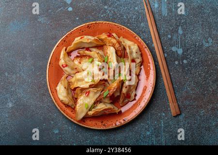 Teller mit Jiaozi- oder Gyoza-Knödeln mit Essstäbchen auf rustikalem Hintergrund, beliebtes Gericht aus China und Japan Stockfoto