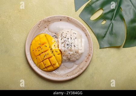 Traditionelles Dessert von Thailand, köstlicher Mango-Kleberreis mit Kokosnussmilch und Sesamsamen auf tropischem Blatt von oben Stockfoto