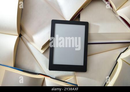Konzept zwischen Digital- und Papierlesen mit eBook auf einem Stapel Papierbücher. Draufsicht Stockfoto