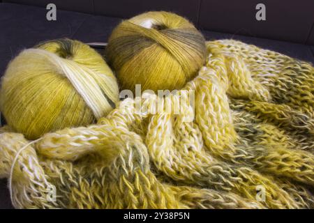 Verlaufsfarbene Garnkugel mit Strickjacke und Stricknadeln. Zitronenfarbene Alpaka- und Wollfäden mit wunderschönem Strickmuster. Stockfoto