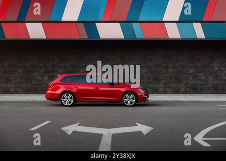 Red Leon Cupra parkte auf der Straße in der Nähe eines modernen Gebäudes. Seitenprofilansicht des sportlichen SITZWAGENS bei Dämmerung. Stockfoto