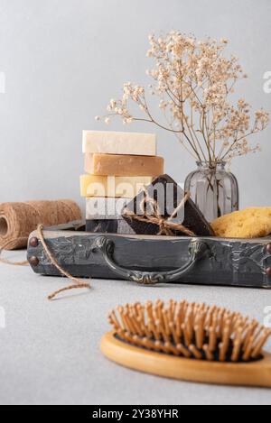 Ein wunderschön gestaltetes Badezimmerset mit handgefertigten Seifen, einer Holzhaarbürste und einem natürlichen Schwamm. Ideal für natürliche Hautpflege, Wellness-Routinen, Stockfoto