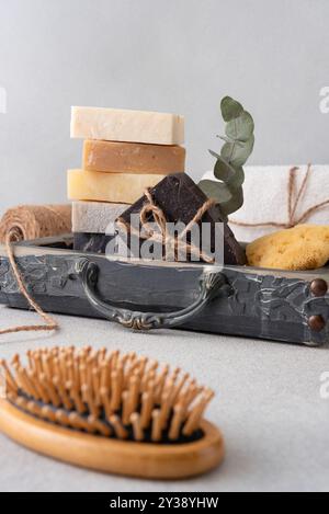 Ein wunderschön gestaltetes Badezimmerset mit handgefertigten Seifen, einer hölzernen Haarbürste und einer Luffa. Ideal für natürliche Hautpflege, Wellness-Routinen und Öko Stockfoto