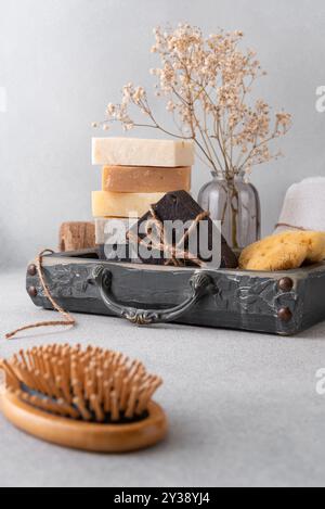 Ein wunderschön gestaltetes Badezimmerset mit handgefertigten Seifen, einer Holzhaarbürste und einem natürlichen Schwamm. Ideal für natürliche Hautpflege, Wellness-Routinen, Stockfoto