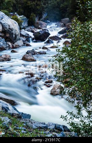 Rauschende Flüsse kaskadieren über Felsen, umgeben von Bäumen Stockfoto