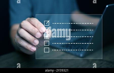 Fragebogen, Umfrage oder Bewertung mit Kontrollkästchen. Ein Mann mit einem Stift, der das Online-Formular auf einem virtuellen Bildschirm mit einer Checkliste ausfüllt, um Fragen zu beantworten Stockfoto