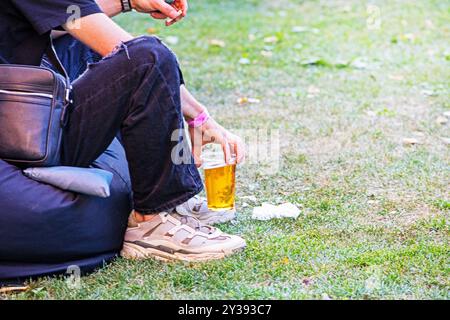 Ein Einwegglas mit Bier und einer Zigarette bei einem Picknick halten. Snack Stockfoto