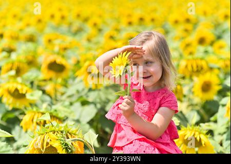 Porträt eines lachenden kleinen Mädchens mit einer Sonnenblume Stockfoto