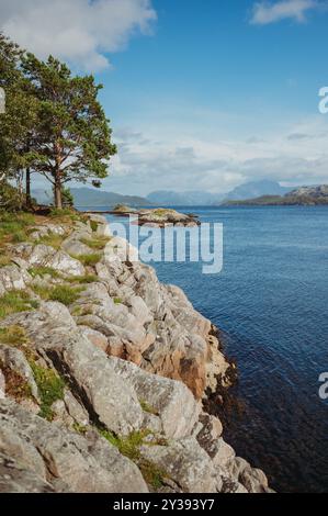 Felsige Küste mit Meer und fernen Bergen in Florø, Norwegen Stockfoto