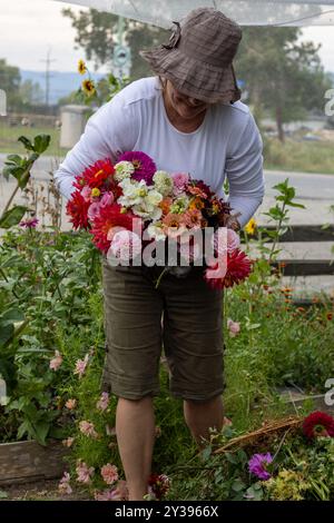 Frau mit einem lebhaften Blumenstrauß in einem Garten Stockfoto