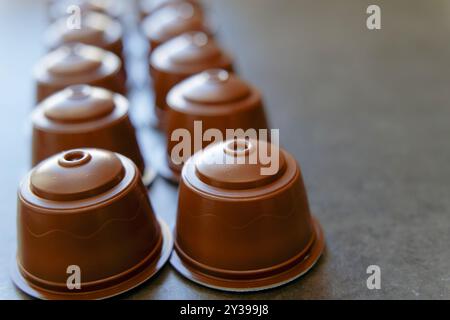 Gruppe von Kaffeekapseln für elektrische Kaffeemaschine in brauner Farbe in einer Reihe mit verschwommenem Hintergrund und Kopierraum Stockfoto