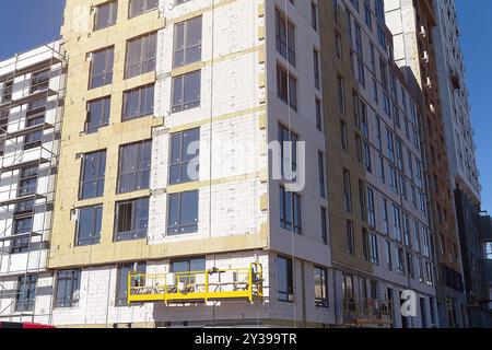 Der Prozess der Dämmung von Außenwänden in einem im Bau befindlichen mehrgeschossigen Gebäude. Konstruktionskonzept. Stockfoto