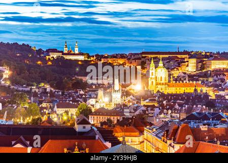 Die Skyline von Prag zeigt die atemberaubende Architektur der Kleinstadt und des Strahov-Klosters, die während des Abends über die Stadt beleuchtet werden und eine magische Atmosphäre schaffen. Stockfoto