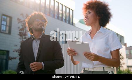 Indischer Mann arabischer Geschäftsmann Investorenkunde und afroamerikanische Frau Makler Verkäuferin Geschäftsfrau spricht zu Fuß in der Stadt und sieht modern aus Stockfoto