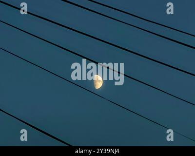 Framed Half Moon by Electricity Cables: A Night Time Sky Composition Stockfoto