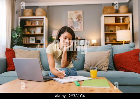Glückliche Frau, die zu Hause arbeitet und Notizen macht Stockfoto
