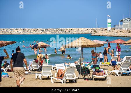 Kusadasi, Türkei - 1. September 2024: Lebhafter Strand in Kusadasi, Türkei, bei Belediye Plaji mit vielen Urlaubern, die Sonne und Meer im Sommer genießen *** Belebter Strand in Kusadasi, Türkei, am Belediye Plaji mit vielen Urlaubern, die Sonne und Meer im Sommer genießen Stockfoto