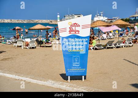 Kusadasi, Türkei - 1. September 2024: Türkisches Zeichen, kostenlose Liegen und Sonnenschirme am Strand von Kusadasi, einem beliebten Urlaubsziel an der türkischen Küste. Der lebhafte Strand lädt zum Sonnenbaden und Schwimmen ein *** Schild auf türkisch, Kostenlose liegen und Sonnenschirme am Strand von Kusadasi, ein beliebtes Urlaubsziel an der türkischen Küste. Der belebte Strand lädt zum Sonnenbaden und Schwimmen ein Stockfoto