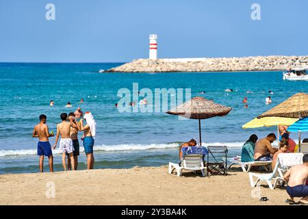 Kusadasi, Türkei - 1. September 2024: Lebhafter Strand in Kusadasi, Türkei, bei Belediye Plaji mit vielen Urlaubern, die Sonne und Meer im Sommer genießen *** Belebter Strand in Kusadasi, Türkei, am Belediye Plaji mit vielen Urlaubern, die Sonne und Meer im Sommer genießen Stockfoto