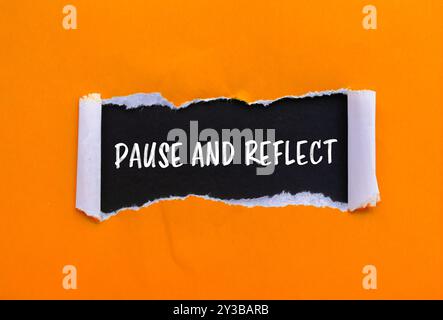 Unterbrechen und reflektieren Sie die Nachricht, die auf gerissenem orangenem Papier mit schwarzem Hintergrund geschrieben wurde. Konzeptionelles Pause- und Reflexionssymbol. Kopierbereich. Stockfoto