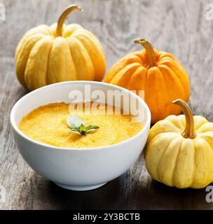 Kürbisbrei und Kürbisse auf schwarzem Holztisch. Stockfoto